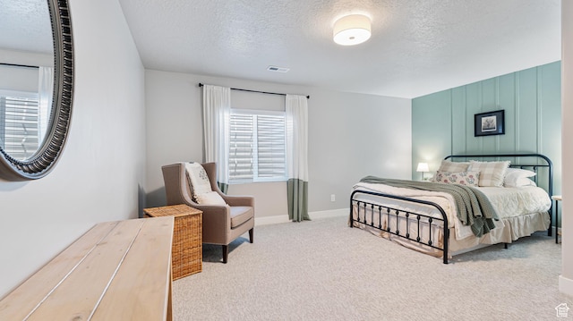carpeted bedroom featuring a textured ceiling, baseboards, and visible vents