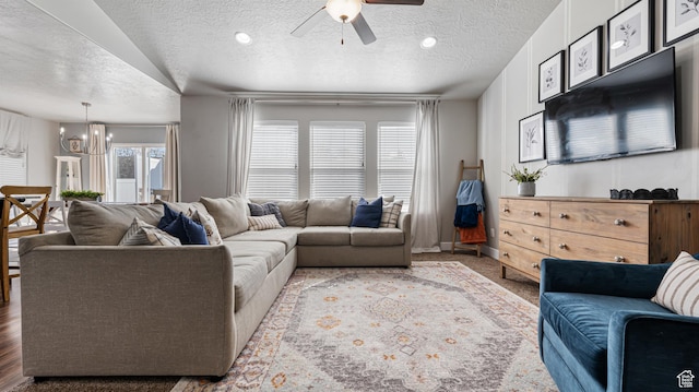 living room featuring a textured ceiling and ceiling fan with notable chandelier