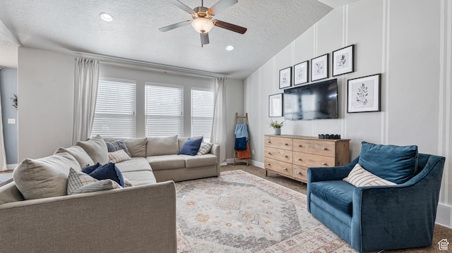 living area with a textured ceiling, baseboards, a ceiling fan, and carpet floors