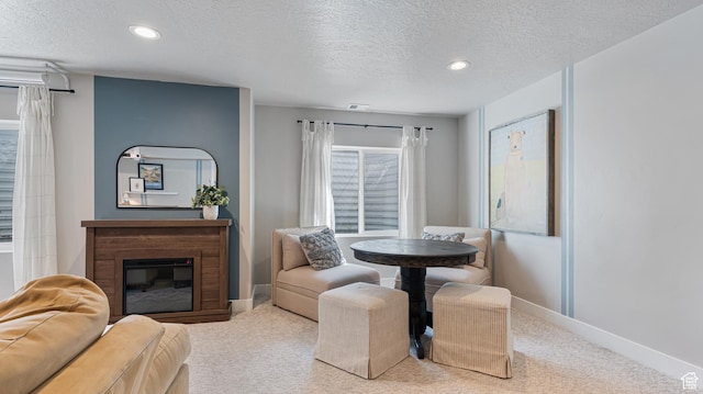 carpeted dining area with a textured ceiling, a glass covered fireplace, visible vents, and recessed lighting