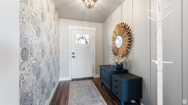 doorway with dark wood-style floors, a textured ceiling, and baseboards