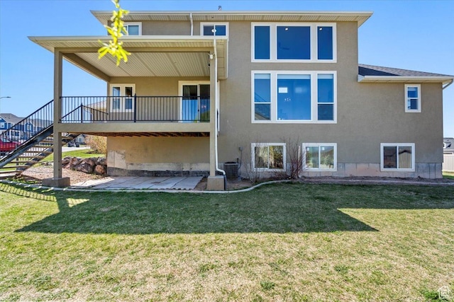 rear view of house with stucco siding, stairway, a patio area, central AC, and a lawn