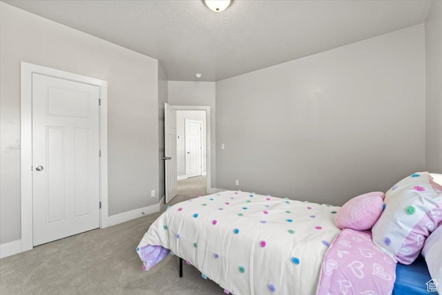 carpeted bedroom featuring a textured ceiling and baseboards