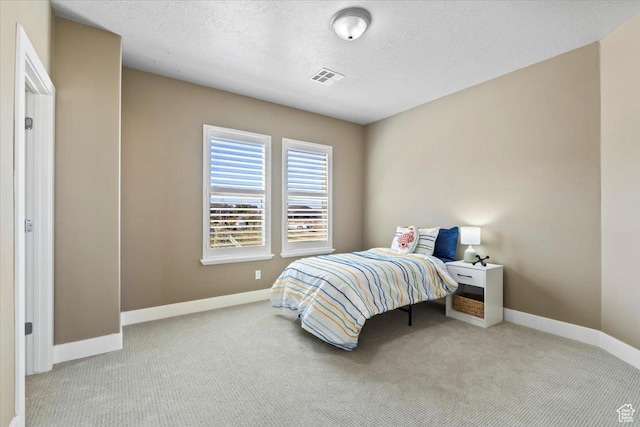 carpeted bedroom featuring visible vents, baseboards, and a textured ceiling