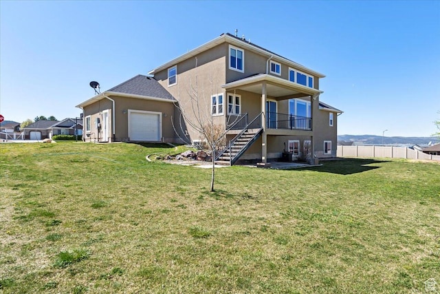 rear view of house featuring stairs, stucco siding, fence, and a yard
