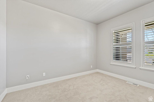 carpeted empty room with visible vents and baseboards