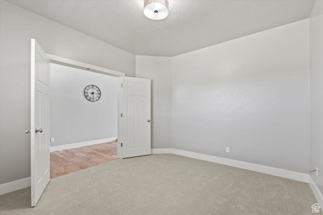 carpeted spare room with baseboards and a textured ceiling