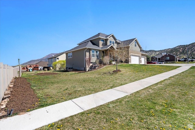 view of front facade with a mountain view, an attached garage, fence, a front lawn, and a residential view
