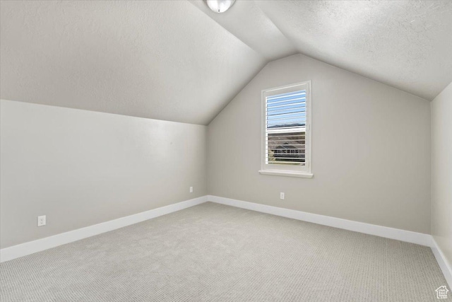 bonus room with baseboards, a textured ceiling, vaulted ceiling, and carpet floors