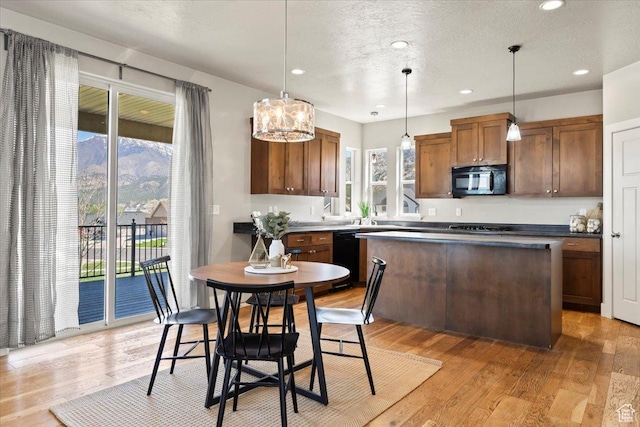 kitchen with decorative light fixtures, a chandelier, black appliances, light wood-style flooring, and a kitchen island