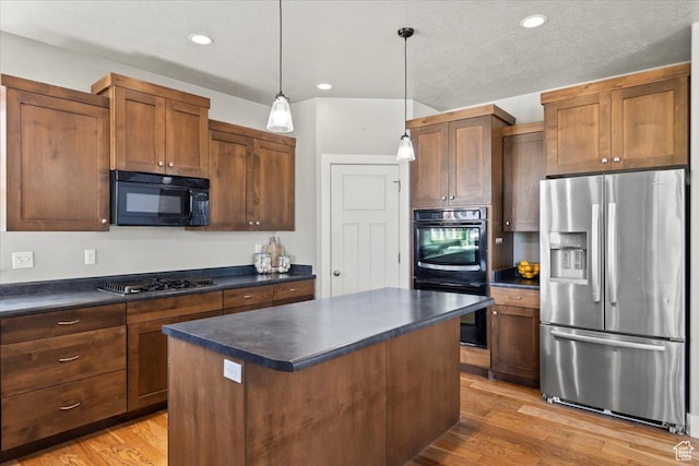 kitchen featuring a center island, dark countertops, light wood-style floors, black appliances, and hanging light fixtures