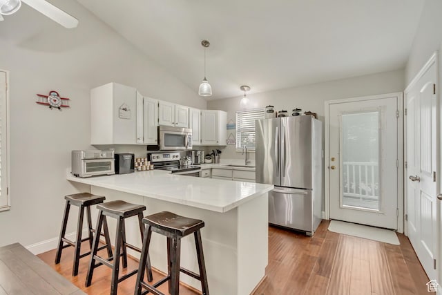 kitchen with a sink, light countertops, appliances with stainless steel finishes, a peninsula, and light wood finished floors