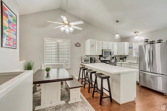 kitchen with a peninsula, white cabinets, ceiling fan, stainless steel appliances, and a sink