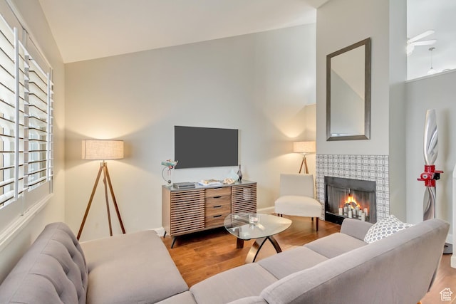 living area featuring wood finished floors, a tiled fireplace, and baseboards
