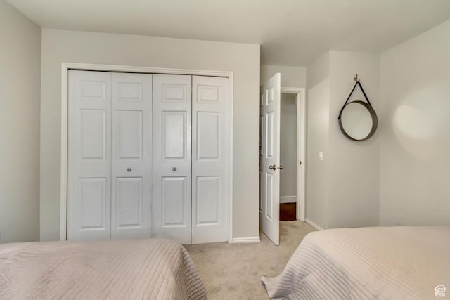 bedroom featuring a closet, baseboards, and light carpet