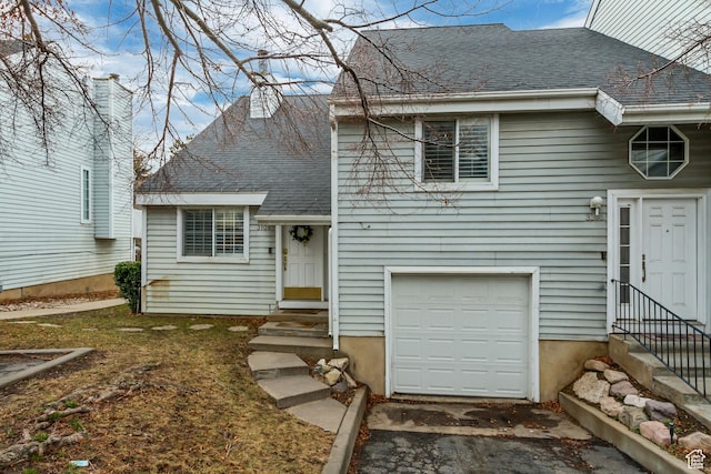 split level home with entry steps, a shingled roof, a garage, and aphalt driveway