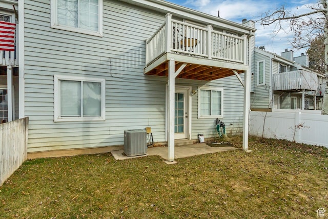 rear view of property with central air condition unit, a patio, fence, and a lawn