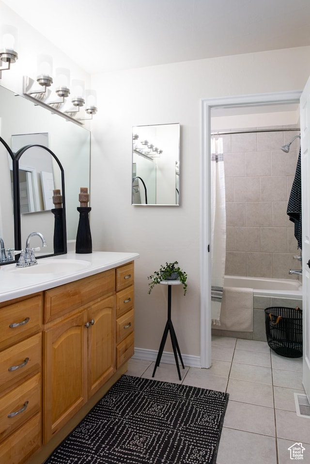 bathroom featuring vanity, tile patterned flooring, visible vents, tiled shower / bath, and baseboards