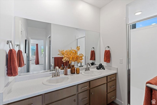 full bath featuring a shower with shower door, double vanity, and a sink