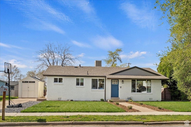 ranch-style house with roof with shingles, a front lawn, brick siding, an outbuilding, and a storage unit
