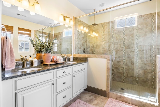 bathroom featuring a stall shower, double vanity, a sink, and visible vents