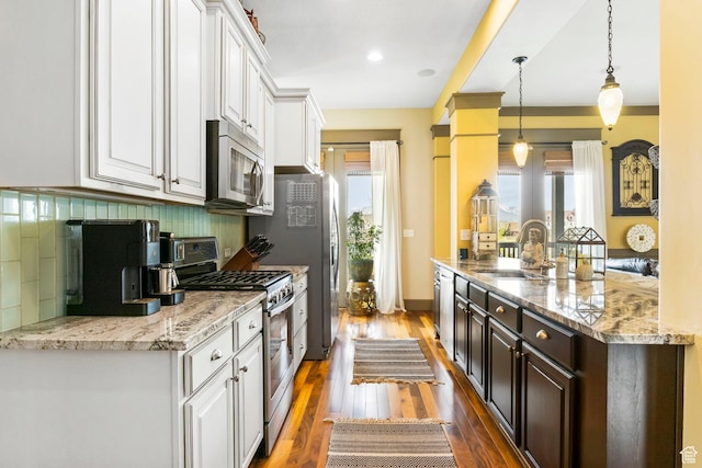 kitchen featuring a wealth of natural light, tasteful backsplash, white cabinets, a sink, and stainless steel appliances