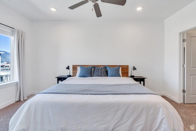 bedroom with a ceiling fan, light carpet, baseboards, and multiple windows