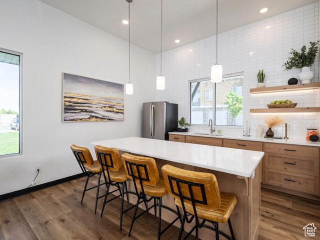 kitchen featuring dark wood-style flooring, a sink, freestanding refrigerator, and backsplash