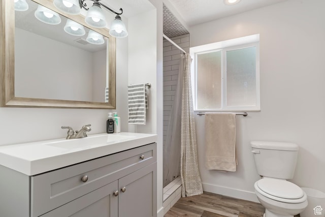 bathroom featuring vanity, visible vents, toilet, wood finished floors, and a stall shower