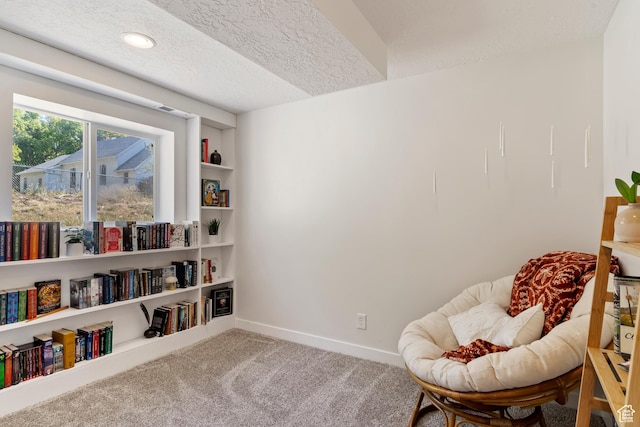 living area featuring carpet floors, baseboards, built in features, and a textured ceiling