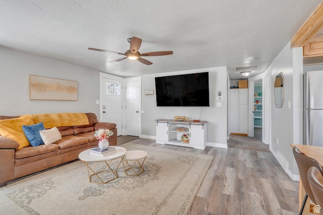 living area with ceiling fan, baseboards, wood finished floors, and a textured ceiling