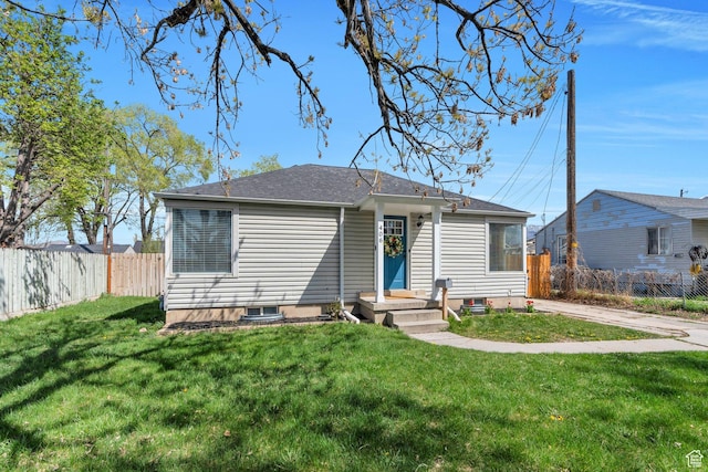 bungalow with a front lawn, fence, and roof with shingles
