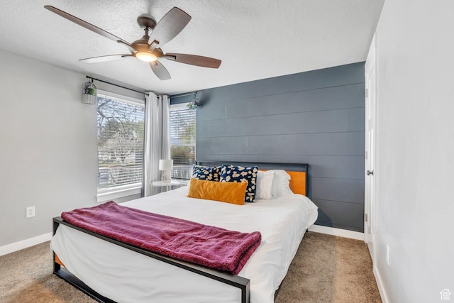 carpeted bedroom featuring baseboards, a textured ceiling, and a ceiling fan