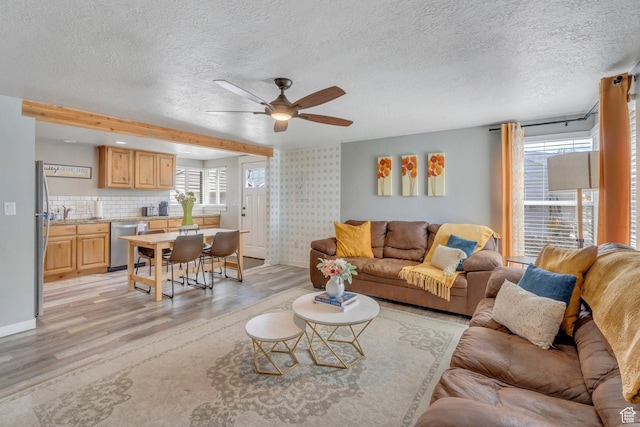 living room with light wood-style flooring, a textured ceiling, and a ceiling fan