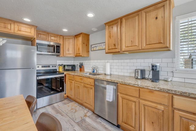 kitchen featuring light wood-style floors, recessed lighting, appliances with stainless steel finishes, a sink, and backsplash