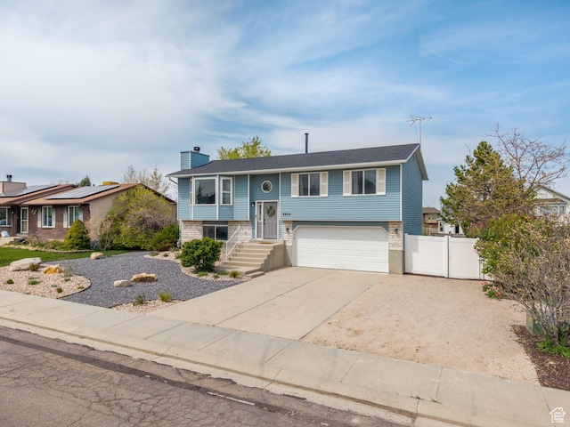 4866 W Diamondleaf Way S, West Jordan, UT 84081 - split foyer home featuring an attached garage, a chimney, fence, concrete driveway, and a gate