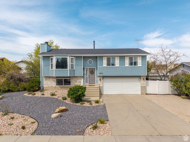 4866 W Diamondleaf Way S, West Jordan, UT 84081 - split foyer home with an attached garage, stone siding, a chimney, fence, and concrete driveway