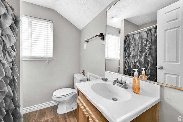 bathroom featuring toilet, a textured ceiling, vanity, wood finished floors, and lofted ceiling