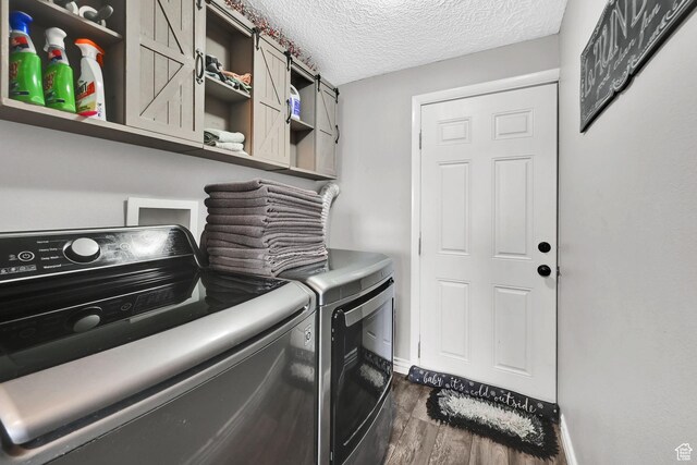 laundry area with dark wood finished floors, a textured ceiling, washing machine and clothes dryer, baseboards, and cabinet space