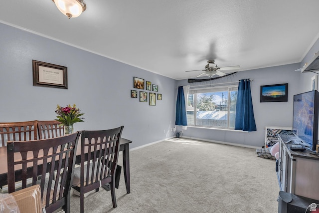 dining space featuring crown molding, ceiling fan, baseboards, and carpet floors