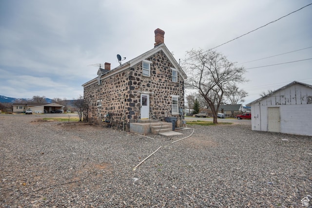 rear view of house with a chimney and stone siding