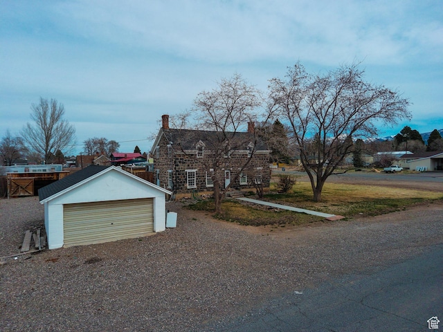 view of front facade with a chimney, a garage, and an outdoor structure