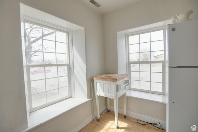 interior space with visible vents, baseboards, plenty of natural light, and wood finished floors