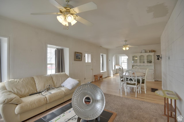 living room featuring light carpet, light wood-type flooring, and a ceiling fan