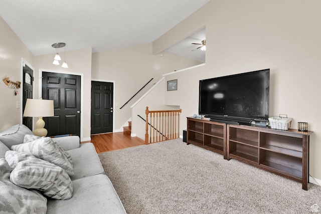 living area with carpet flooring, ceiling fan, vaulted ceiling with beams, and stairway