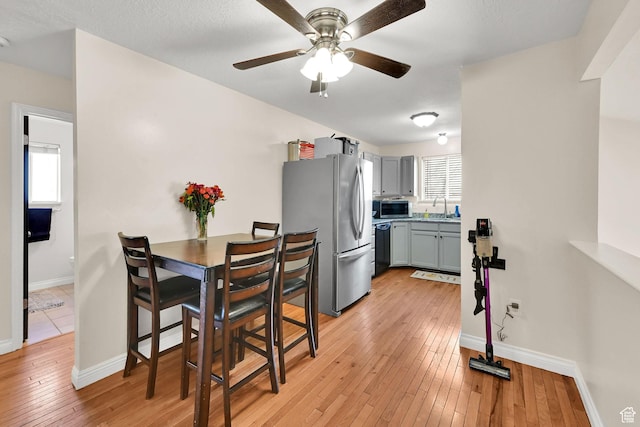 dining area with light wood-style flooring, baseboards, and a ceiling fan