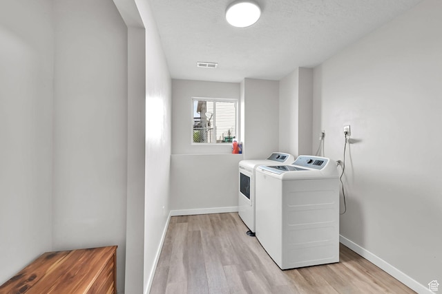 laundry room featuring visible vents, baseboards, washer and dryer, laundry area, and light wood finished floors