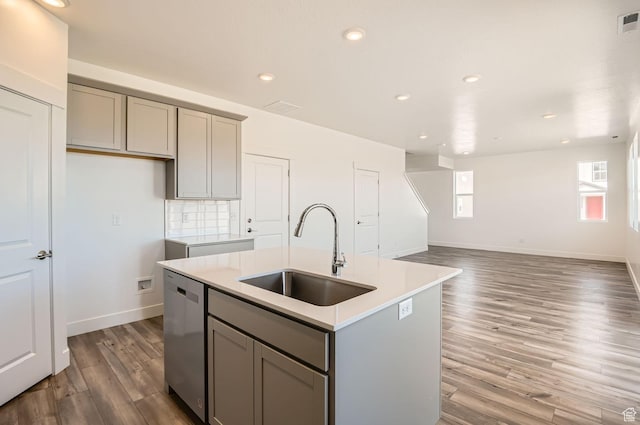 kitchen with a sink, an island with sink, gray cabinetry, and dishwasher