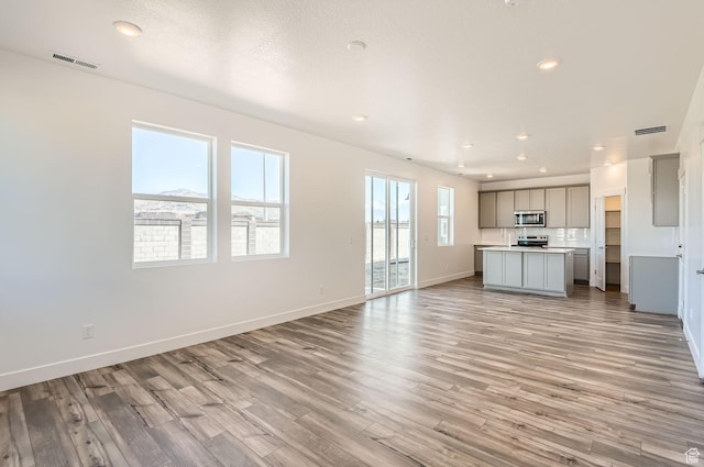 unfurnished living room featuring recessed lighting, light wood finished floors, visible vents, and baseboards