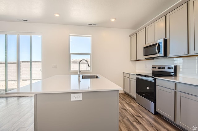 kitchen with plenty of natural light, a sink, appliances with stainless steel finishes, gray cabinets, and backsplash